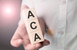A hand holding the letters that spell out ACA